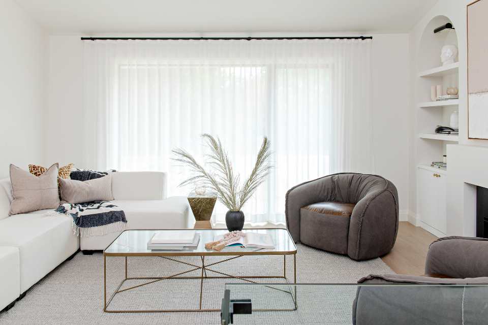 neutral living room with gold coffee table, sheer blinds and pink accents